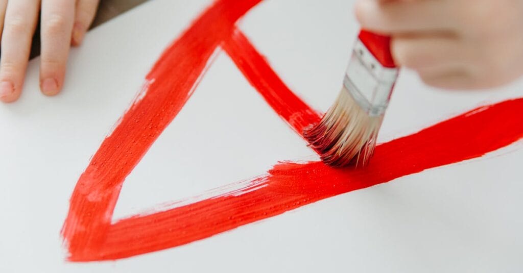 A child painting with red brush strokes on a white canvas, showcasing creativity and art education.