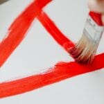 A child painting with red brush strokes on a white canvas, showcasing creativity and art education.