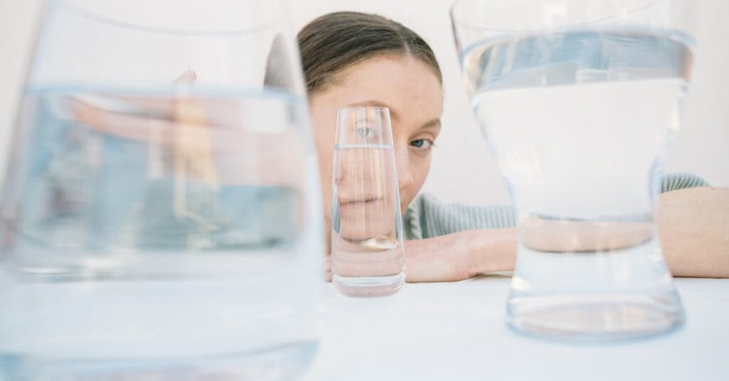 Creative portrait view distorted through various glass cups on a white background.