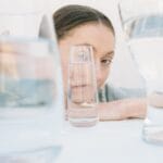 Creative portrait view distorted through various glass cups on a white background.