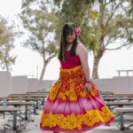 Young girl wearing a colorful dress with floral patterns in an outdoor park setting, enjoying a carefree moment.