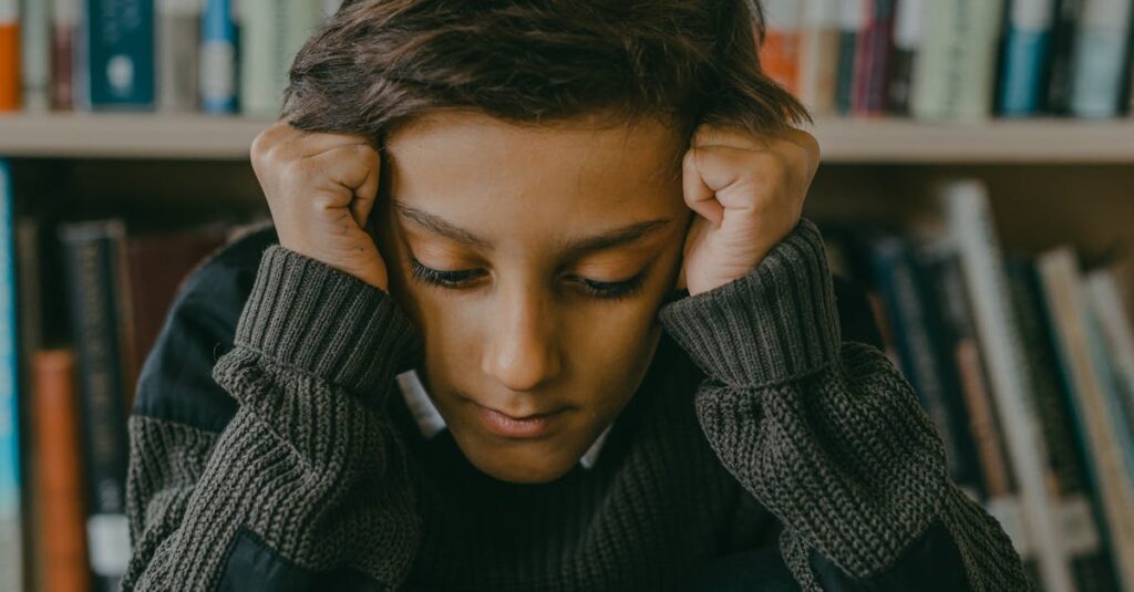 A distressed child sits on the floor in a library with books in the background, embodying sadness.
