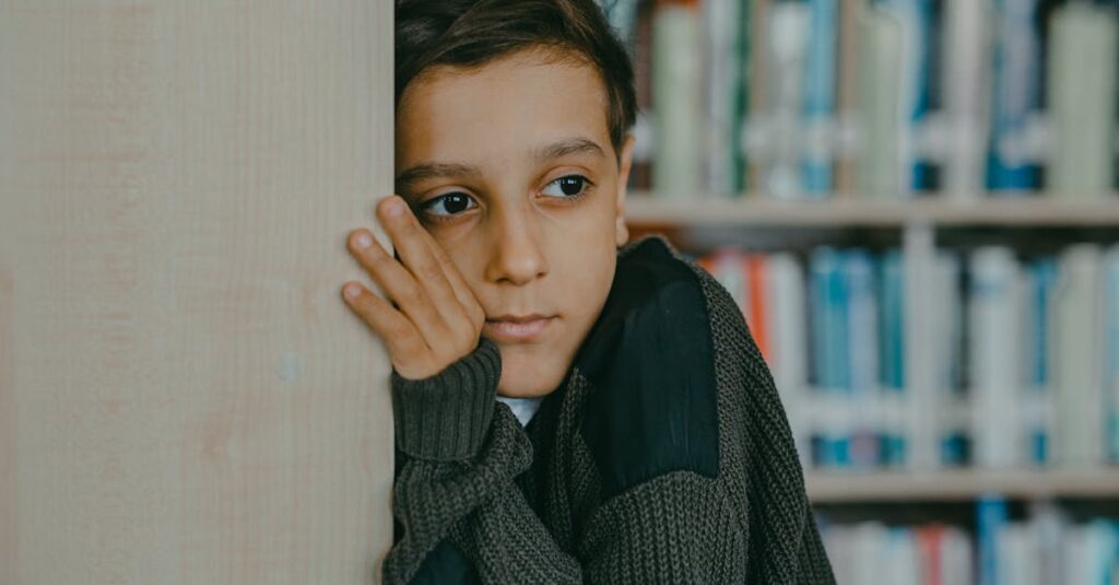 A contemplative child leans against a wall in a library, deep in thought.