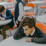 A young child feeling left out in a school classroom surrounded by peers.