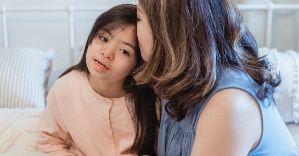 Warm and loving interaction between a mother and her daughter in a cozy bedroom setting.
