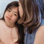 Warm and loving interaction between a mother and her daughter in a cozy bedroom setting.