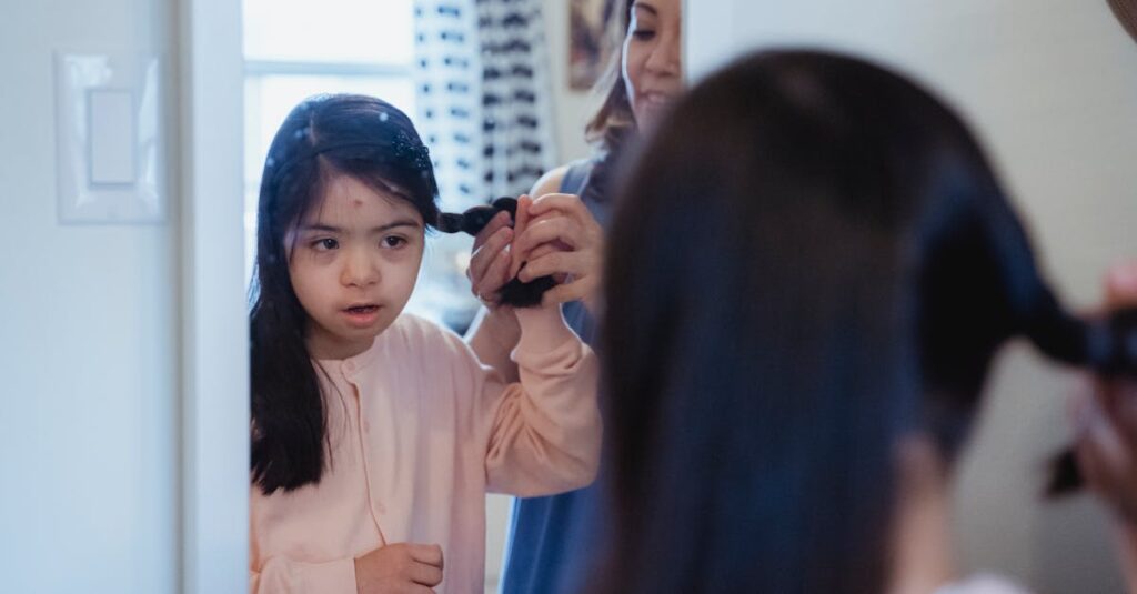 Mother braiding her daughter's hair while the girl looks in the mirror, creating a warm family moment.