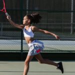 Dynamic shot of a teen girl playing tennis outdoors, showcasing athletic movement and sportswear.