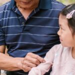 An affectionate moment between a grandfather and granddaughter enjoying time outdoors.