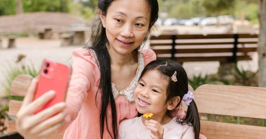 A joyful mother and daughter share a moment taking a selfie at the park.