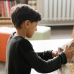 Young boy reading a comic book in a cozy library. Captured indoors on a quiet day.
