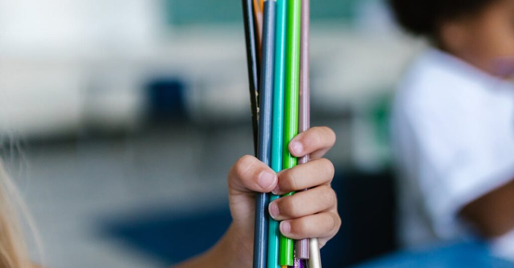Two children holding a bunch of colorful pencils, indoors in a learning environment.