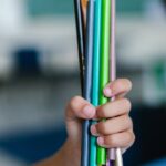 Two children holding a bunch of colorful pencils, indoors in a learning environment.