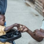 A father and baby bond as they share food outdoors, capturing a moment of love and parenthood.