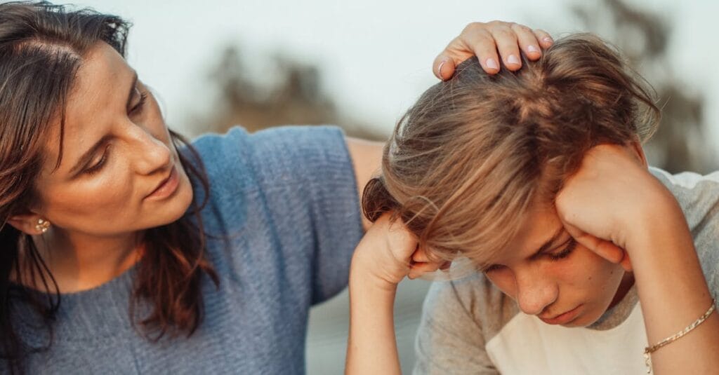 A mother offers support to her discouraged teenager son, portraying love and understanding.
