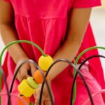 A young girl engages with colorful educational toys in a vibrant classroom setting.