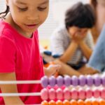 Happy children exploring an abacus in a lively classroom setting.