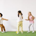 Happy children enjoying a tug of war game indoors, showcasing teamwork and fun.