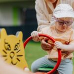 A playful moment between mother and child on a colorful playground seesaw outdoors.