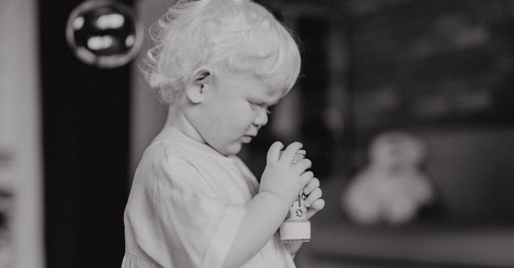 Charming black and white portrait of a toddler with curly hair holding a toy indoors.