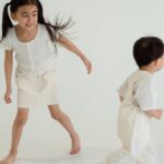 Joyful siblings playing together in a bright, minimalist studio setting.