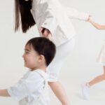 Joyful family of three playing and laughing in a bright studio setting.