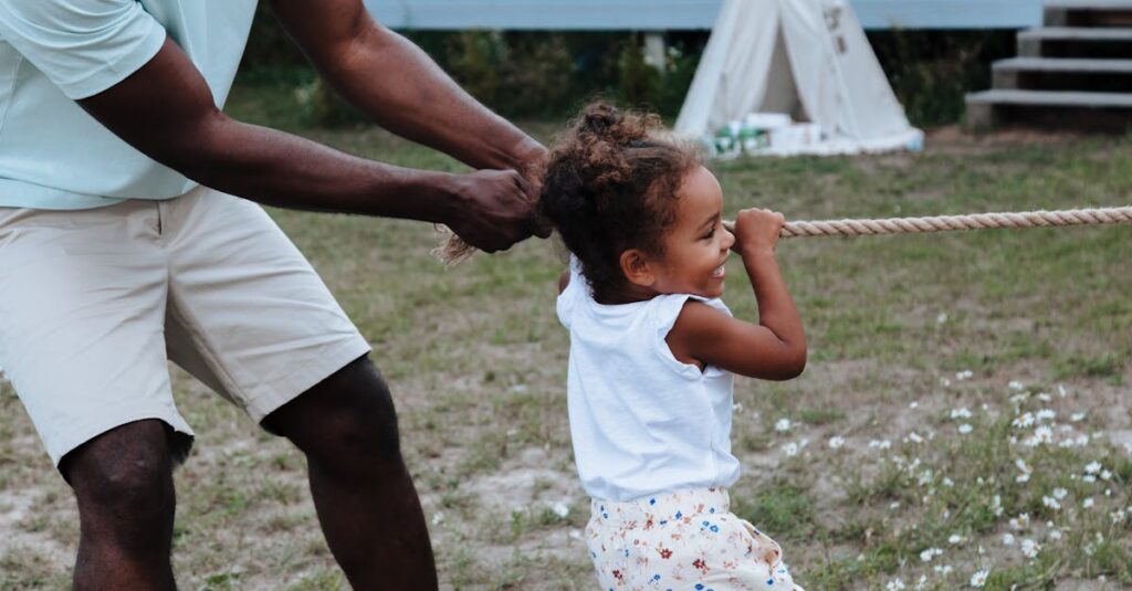Father and daughter playing tug of war outdoors, capturing a playful moment.