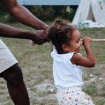 Father and daughter playing tug of war outdoors, capturing a playful moment.