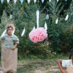 Kids having fun in a sack race during a backyard party set outdoors in summer.