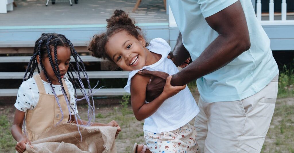 Joyful family moment with father and daughters playing outdoors in the yard.