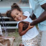 Joyful family moment with father and daughters playing outdoors in the yard.