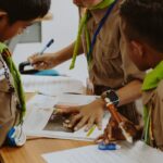 Children in school uniforms working together at a desk in a classroom.