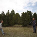 Mother and child enjoying playtime in lush Swiss landscape with trees.