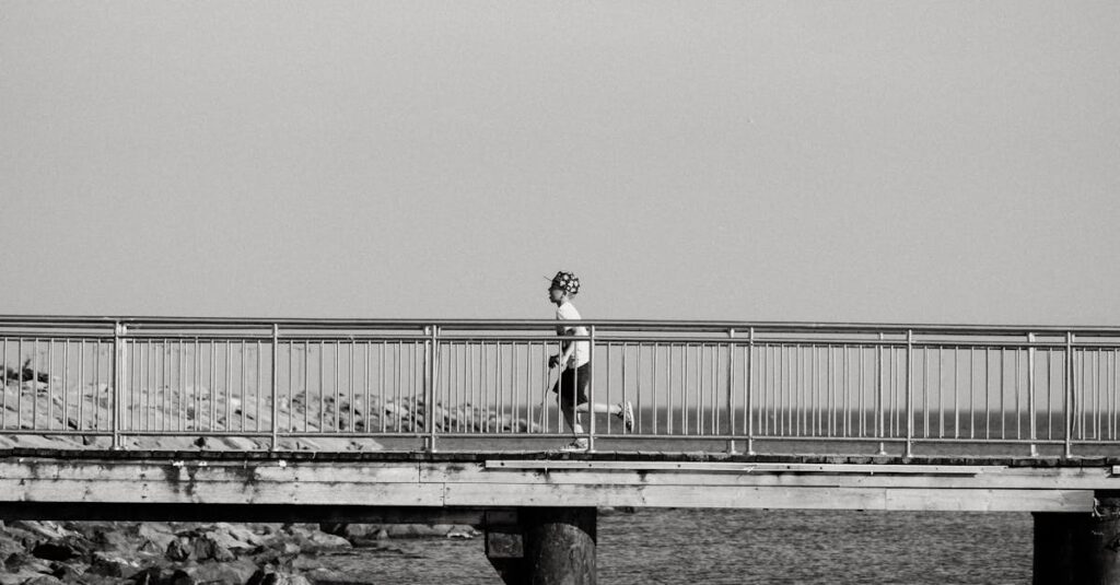 A young boy in a cap runs across a seaside bridge in a black and white setting.