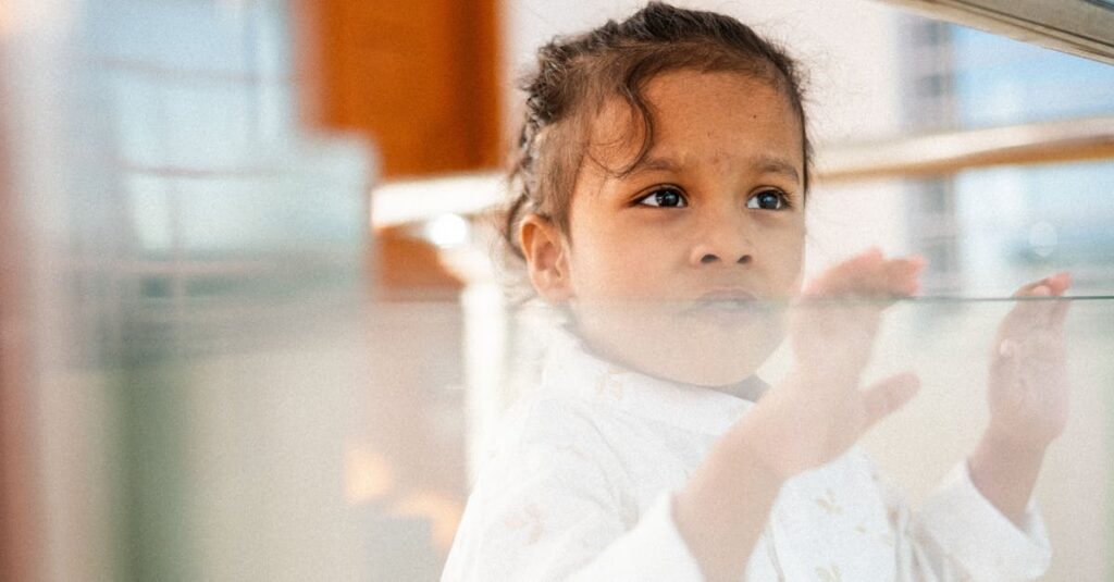 A young girl gazes through a glass panel, indoors, capturing curiosity and innocence.