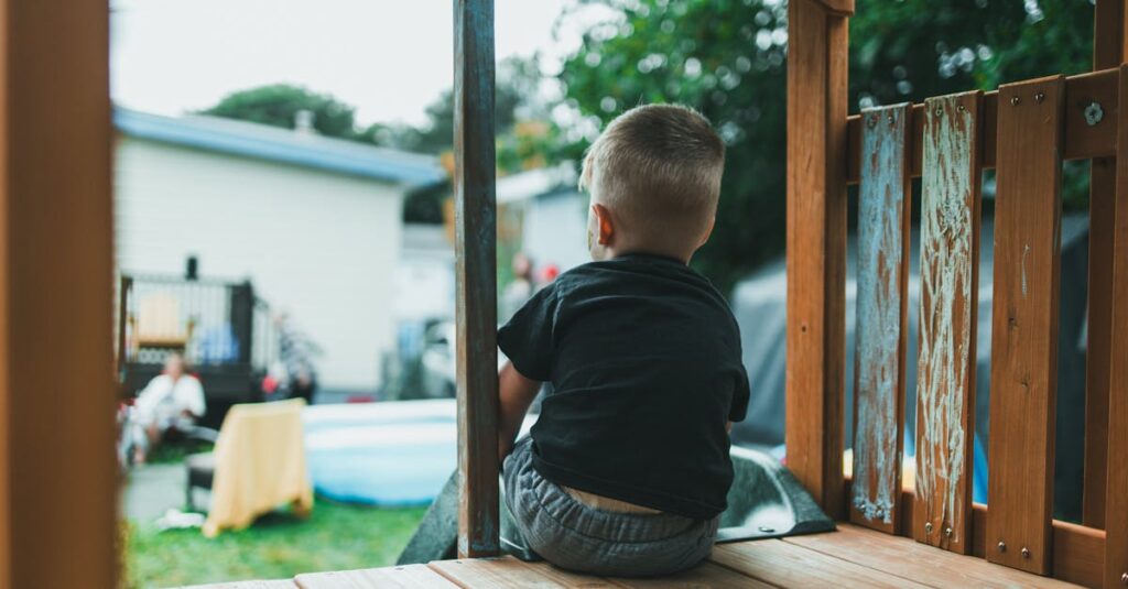 Rear view of a child enjoying a summer day on a backyard playground slide.