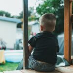 Rear view of a child enjoying a summer day on a backyard playground slide.
