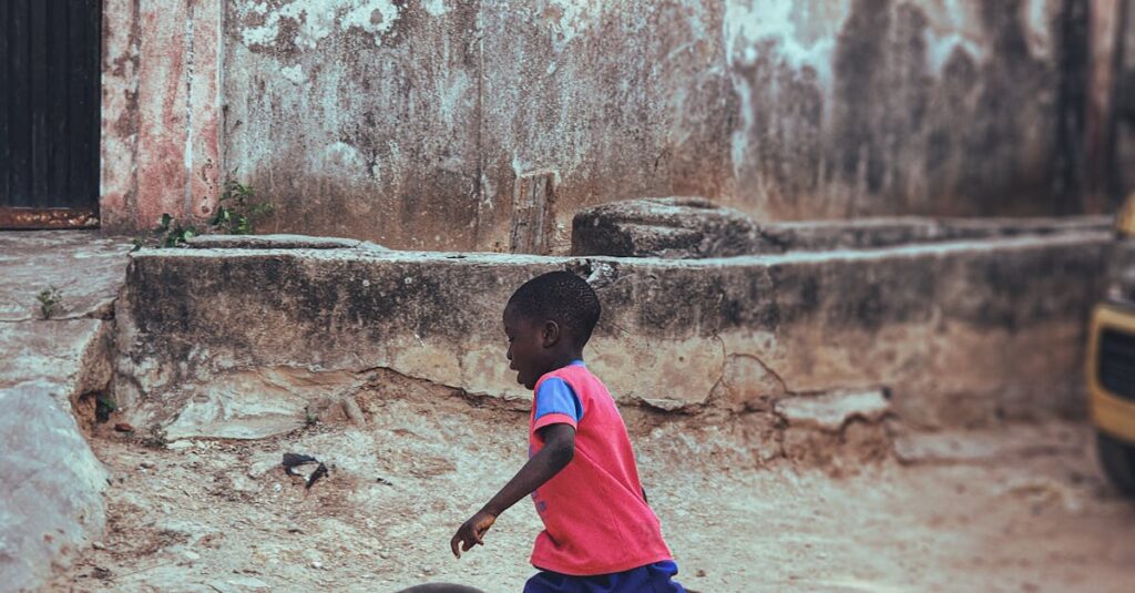 A joyful child in a colorful outfit running and playing with a bicycle tire outdoors.