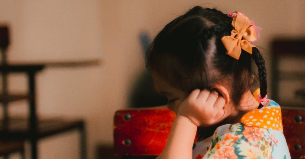 A young girl engrossed in reading a book in an indoor classroom setting.