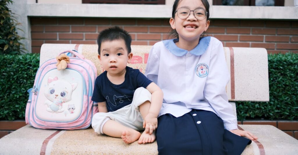 Two children sit on a bench outdoors, showcasing sibling bonding and school life.