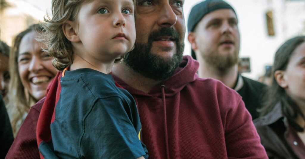A father and his child enjoying a live outdoor music concert in daylight.