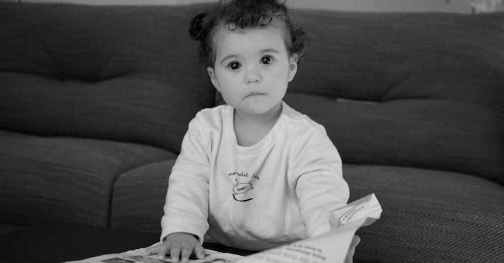 Cute baby engaged and curious while looking at a book indoors.