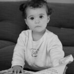 Cute baby engaged and curious while looking at a book indoors.
