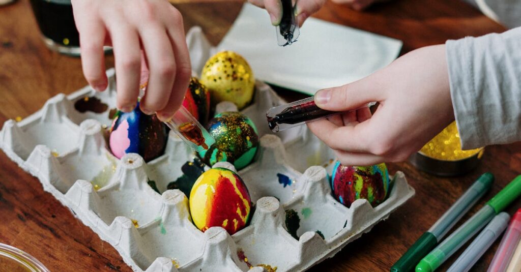 Children decorating colorful Easter eggs on a wooden table, engaging in a fun and creative activity.
