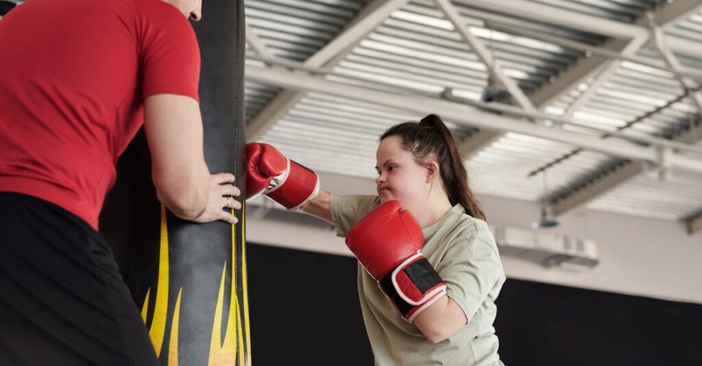 A woman with Down syndrome energetically trains boxing with a coach in a gym setting.