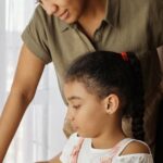 A mother helps her daughter with homework, highlighting education and family bonding indoors.