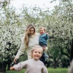 A joyful family enjoys a playful day outdoors amidst blossoming trees in spring.