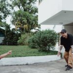 Father and child playing outside a modern detached house, surrounded by greenery.
