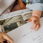 A mother writing while holding her baby in a cozy home office setting, illustrating multitasking.
