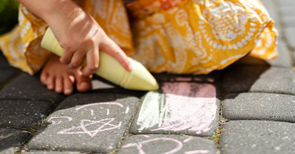 A child drawing colorful chalk art on paved ground, showcasing creativity.